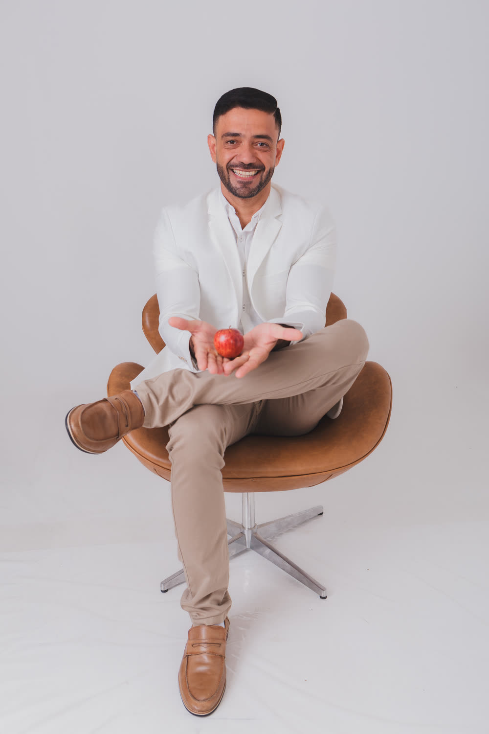Dr. Anísio Filho sorrindo, sentado, segurando uma maçã na mão